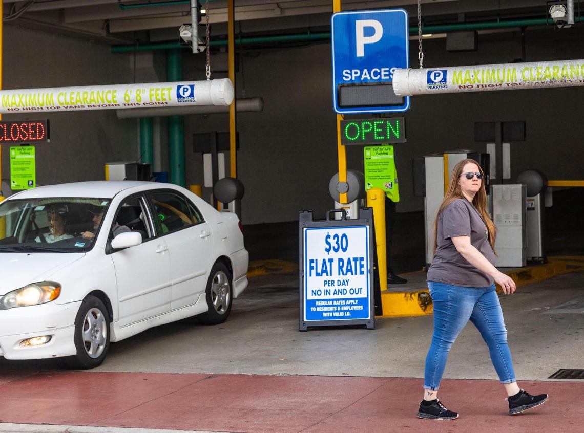 A pedestrian walks by a parking garage in Miami Beach with a sign that shows a $30 flat fee for parking on Feb. 29, 2024.