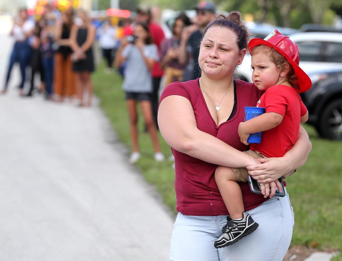 Amelia Wisehart with her son Travis, 2, watches the funeral procession for Kevin Mehaffey, a firefighter paramedic and driver engineer with the Pembroke Pines Fire Rescue Department, May 21, 2020. He died in an off-duty car accident. A large multi-agency procession in his honor traveled on Pines Boulevard between Douglas Road and 103rd Ave.