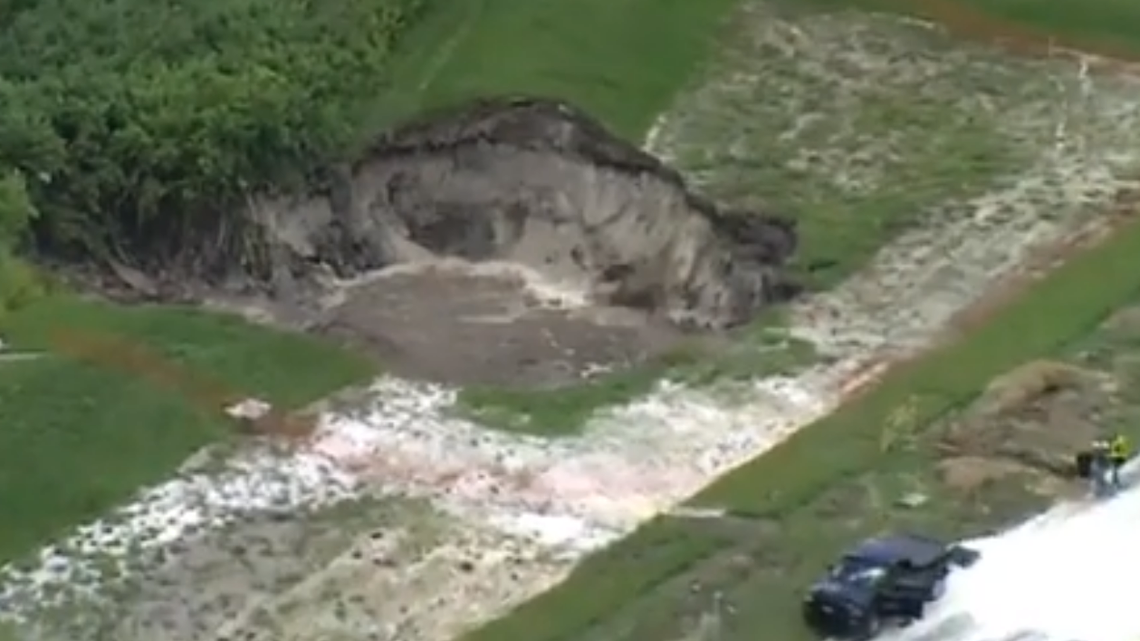 A large sinkhole is continuing to grow in a Florida neighborhood, prompting government officials to warn three homeowners, according to Polk County officials.