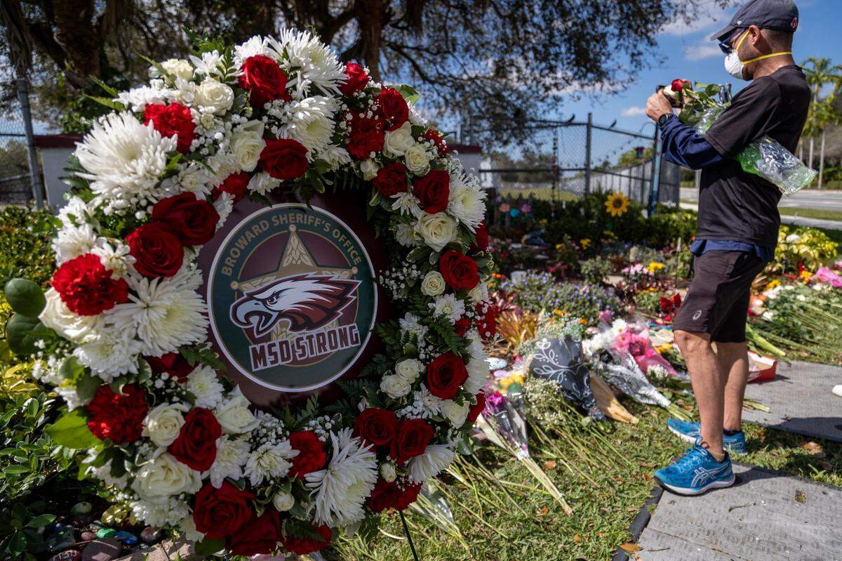 A man takes a photo of a memorial at Marjory Stoneman Douglas High School in Parkland on Feb. 14, 2023.