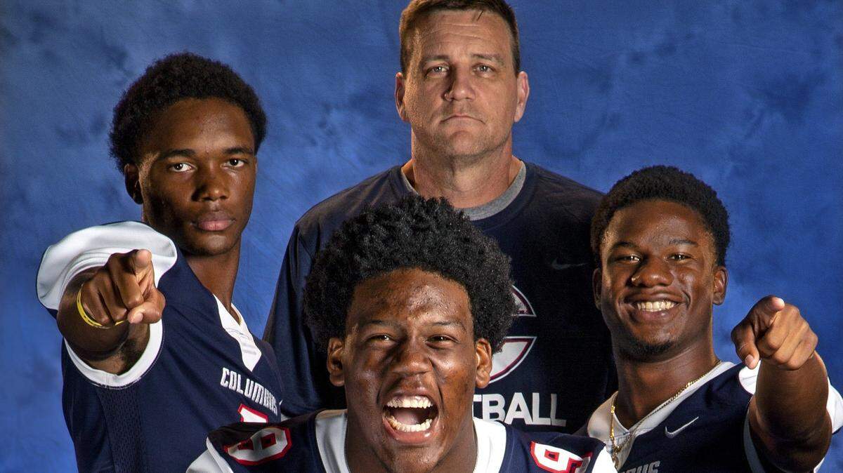 Xzavier Henderson (3), coach Dave Dunn and Henry Parrish (2), at top, left to right, and Elijah Roberts (9), at front at Christopher Columbus High School for Miami-Dade County High School Football Season Preview on Tuesday, August 20, 2019.