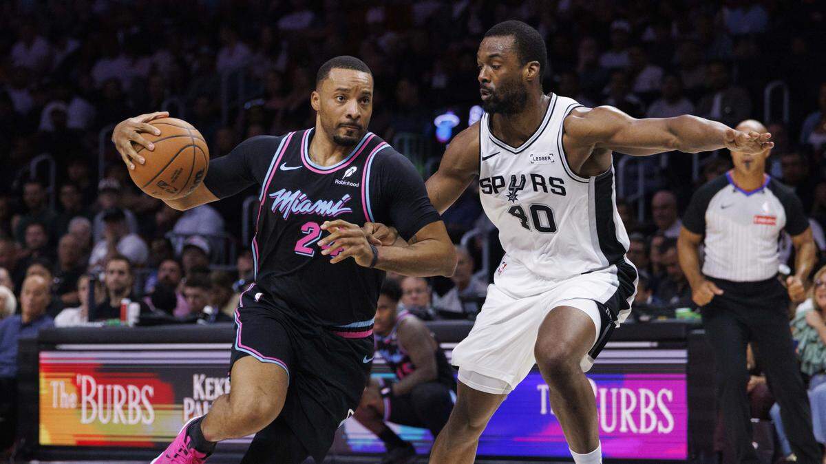 Miami Heat guard Norman Powell (24) dribbles around San Antonio Spurs forward Harrison Barnes (40) during the first half of the game on March 23, 2026, at Kaseya Center in Miami.