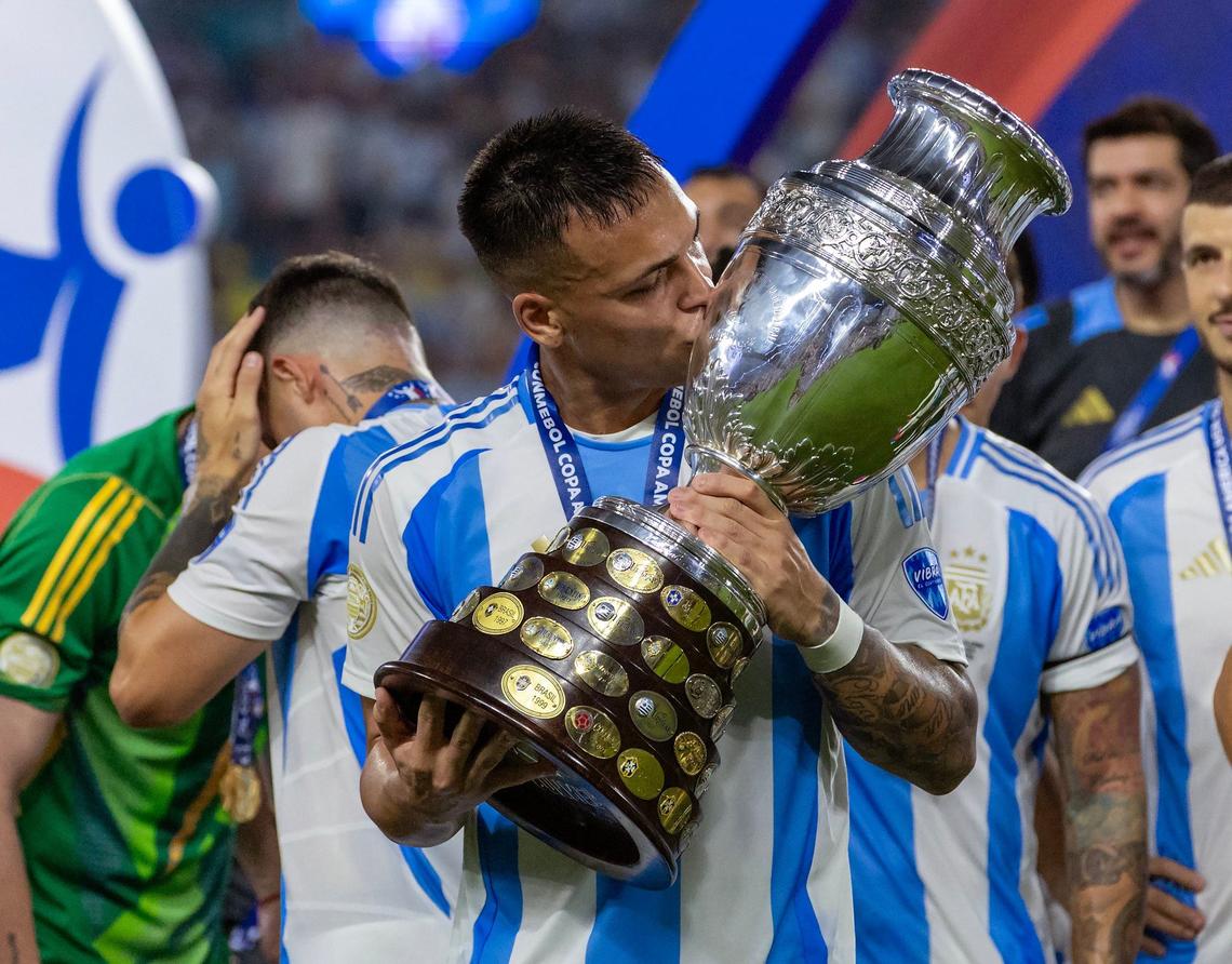 Argentina forward Lautaro Martínez (22) kisses the trophy with his teammates after defeating Colombia in their Copa America 2024 Final soccer match at Hard Rock Stadium on Sunday, July 14, 2024, in Miami Gardens, Fla.
