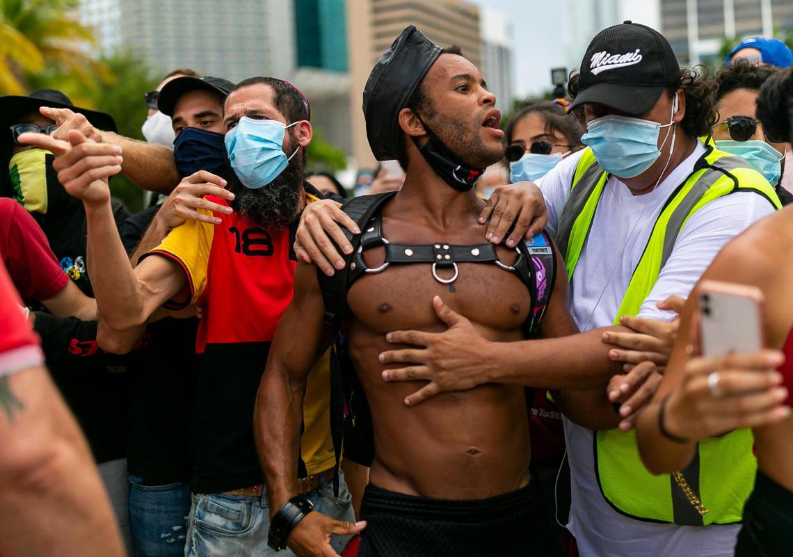 Members of an anti-police brutality rally hold back Jonathan Gartrelle, 31, as their protest was confronted by a Law and Order Rally near the Pepper Fountain at Bayfront Park in downtown Miami on Sunday, June 14, 2020.