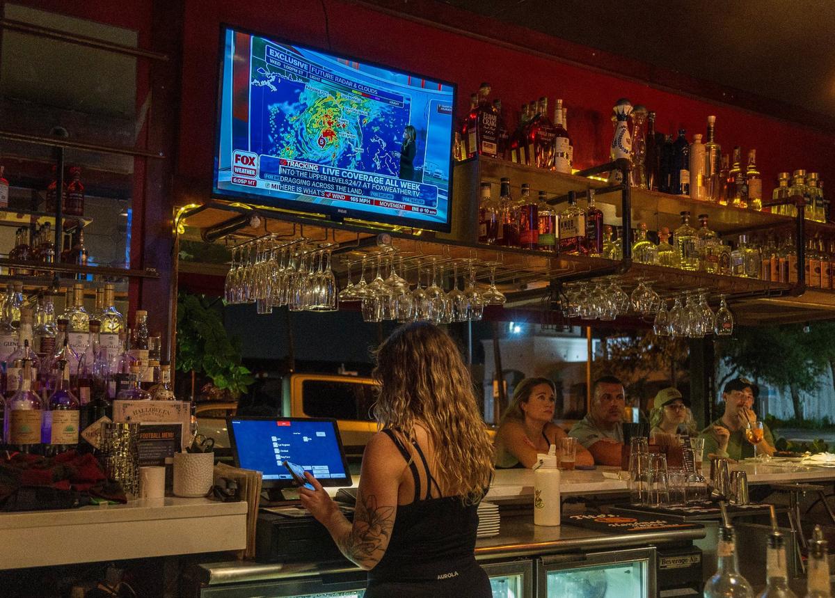 Live updates on Hurricane Milton are seen on tv as patrons drink and dine at the Copperhead Tavern’s bar in Melbourne Beach, as the hurricane approaches the West coast of Florida and then makes its way to the East coast, on, Tuesday October 08, 2024.