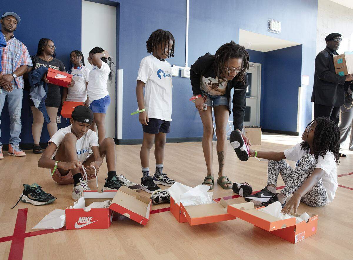 Jakia Battle helps her children DiMir, Marlo and Ma'Lei to try on Nike's sneakers they received as a gift at the Prison Fellowship Angel Tree sports camp on Saturday, November 15, 2025 in Miami. Andrew Uloza / for Miami Herald