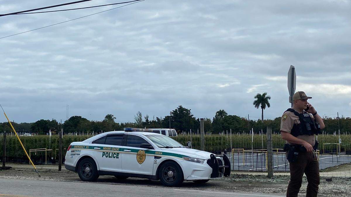 A Miami-Dade cop stands by a police car at 232nd Street and 162nd Avenue on Thursday, Jan. 18, 2024, hours after a man shot two officers near the Redland in south Miami-Dade the night before. The man was shot and killed by police, authorities said.
