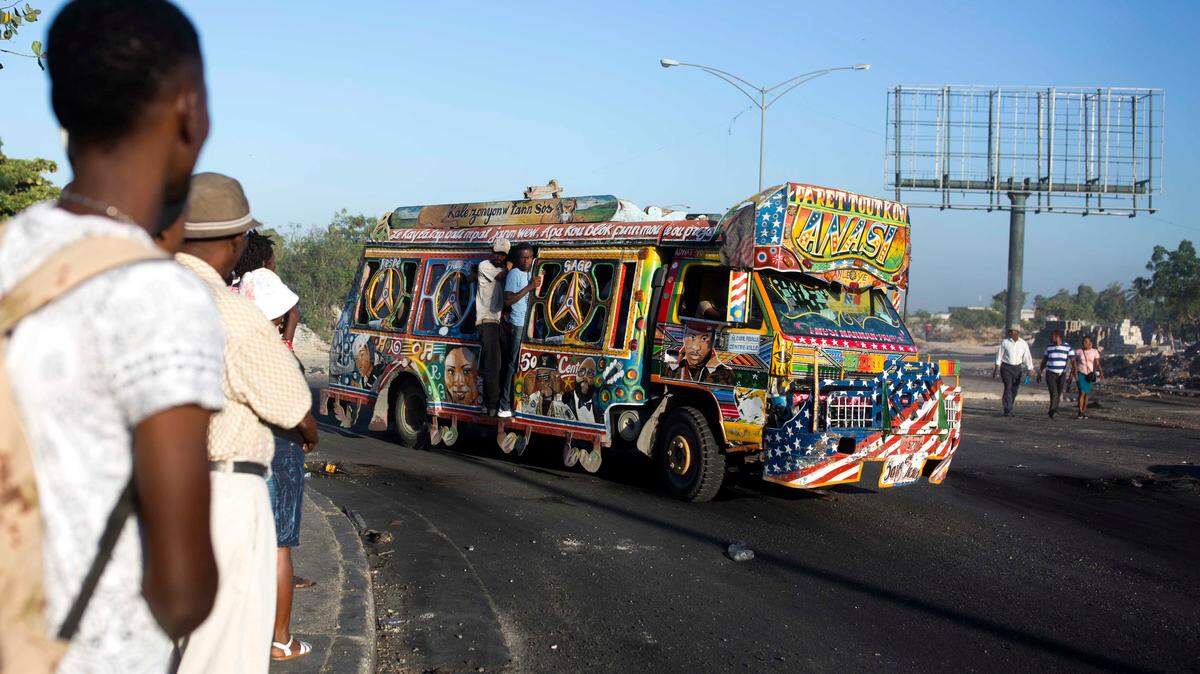 A painted bus filled with passengers makes its way along the street on the second day of a nationwide general strike in Port-au-Prince, Haiti, early Tuesday, July 10, 2018. While some opposition leaders called off the strike for Tuesday, most businesses remained closed following days of violent protests against a 50 percent fuel hike, part of a plan endorsed by the IMF to modernize the economy, and calls for the resignation of President Jovenel Moïse, whose government suspended the hike.