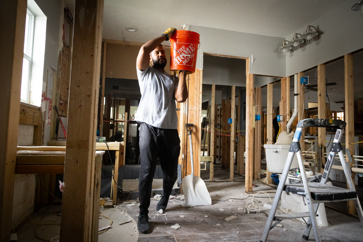 A contractor carries pieces of drywall out from Martin’s house.