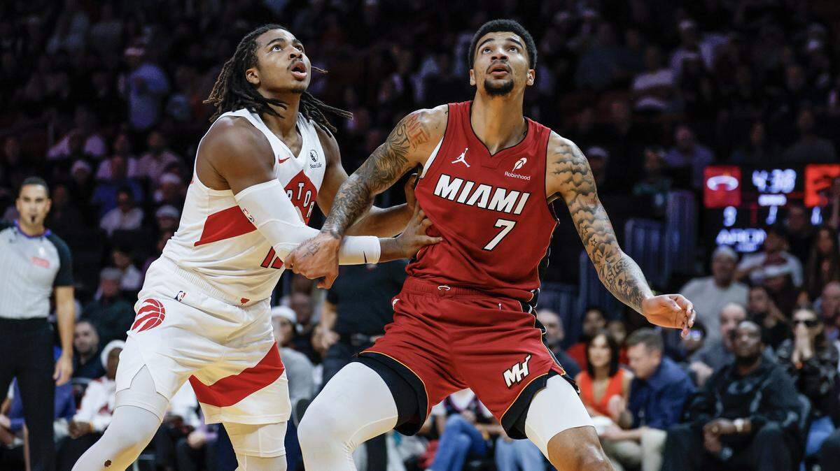 Toronto Raptors forward Collin Murray-Boyles (12) and Miami Heat center Kel'El Ware (7) keep an eye on the rebound during the first half of their NBA basketball game at Kaseya Center in Miami on December 23, 2025.