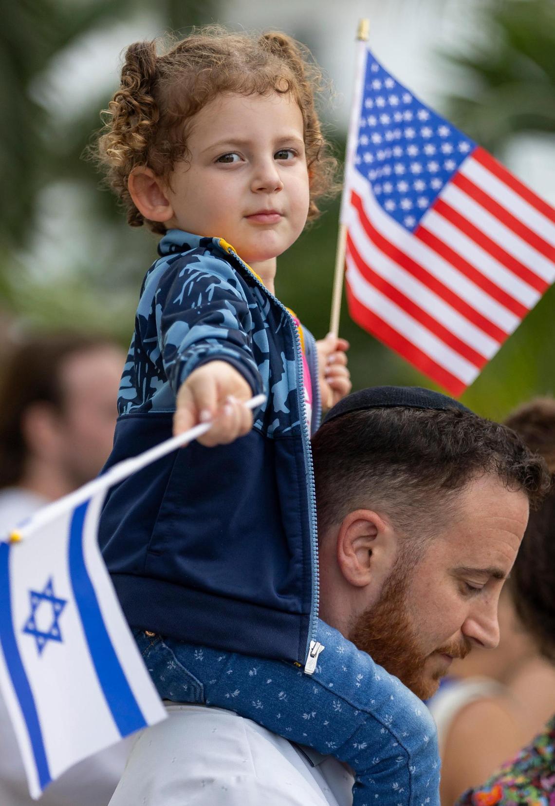 Fay, 3, sits on the shoulders of her father, Menachem, 33, at the rally at the Holocaust Memorial on Tuesday, Oct. 10, 2023, in Miami Beach, Fla.
