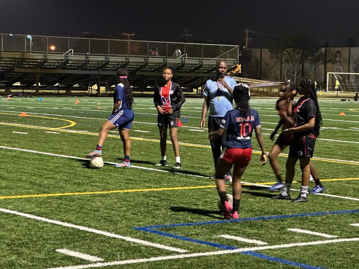 Members of the Edison girls’ soccer team receive instruction from one of their coaches just as practice begins on Monday night at Little Haiti Soccer Park.