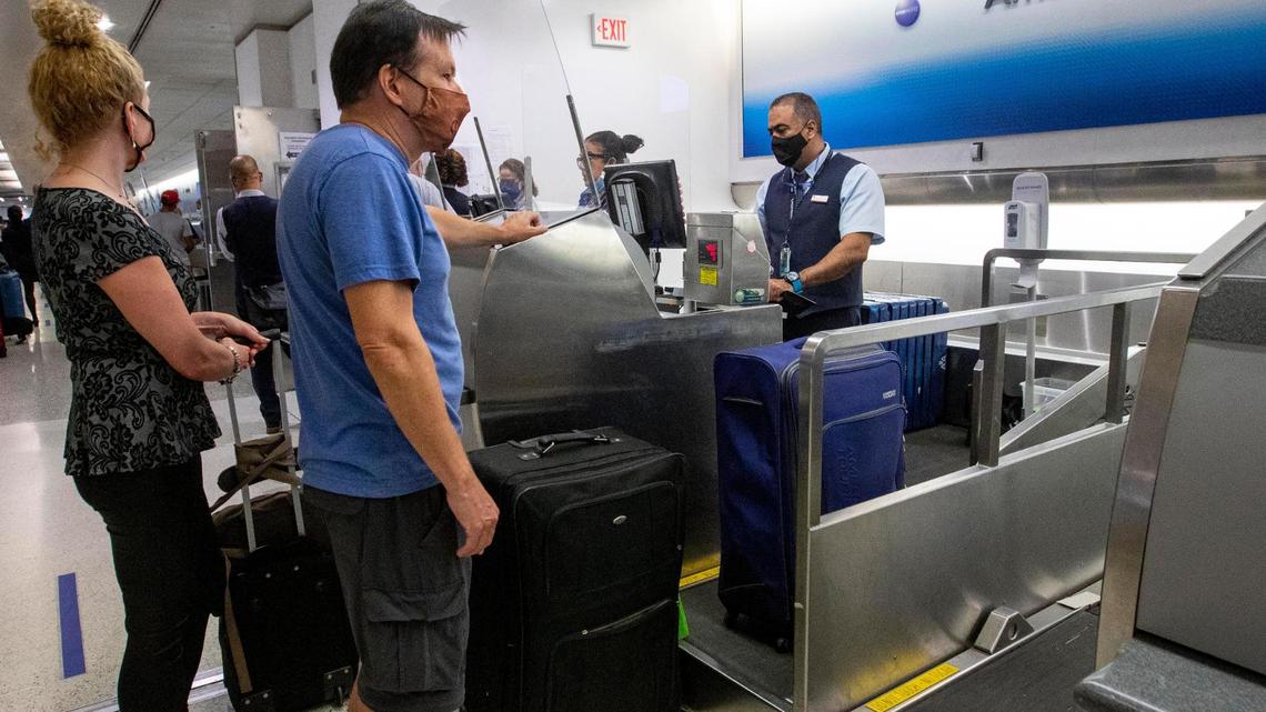 Canadian citizens Patty and Greg Miller speak with an American Airlines employee while checking in, using VeriFLY, a smartphone app that lets people upload documentation proof of negative COVID test or vaccine proof, before their international flight from Miami International Airport in Miami, Florida, on Monday, June 7, 2021.