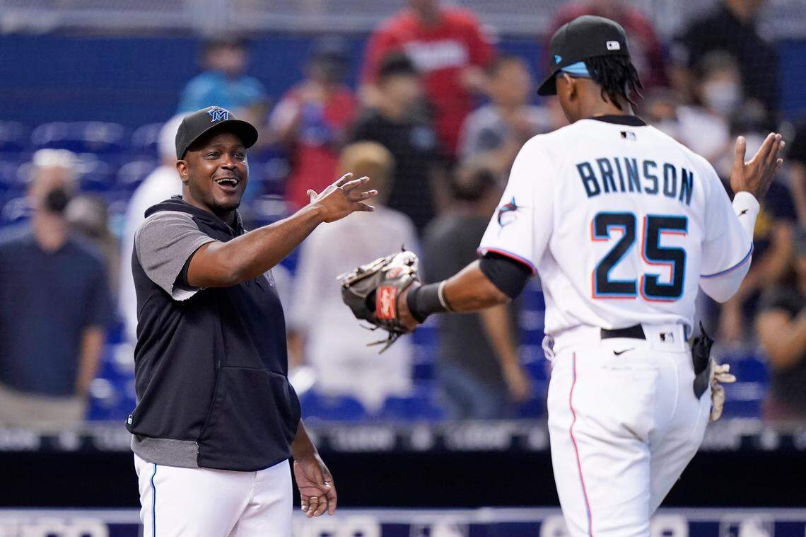 Miami Marlins bench coach and acting manager James Rowson, left, greets Lewis Brinson (25) after a baseball game against the New York Mets, Thursday, Aug. 5, 2021, in Miami. The Marlins won 4-2. (AP Photo/Lynne Sladky)