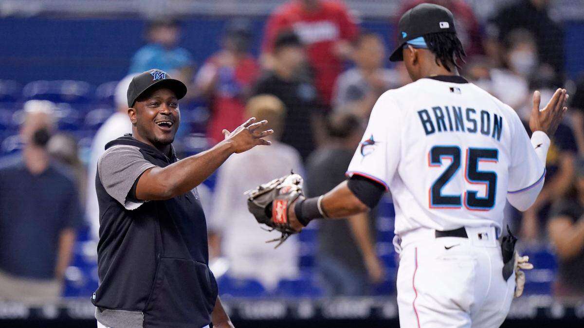 Miami Marlins bench coach and acting manager James Rowson, left, greets Lewis Brinson (25) after a baseball game against the New York Mets, Thursday, Aug. 5, 2021, in Miami. The Marlins won 4-2. (AP Photo/Lynne Sladky)