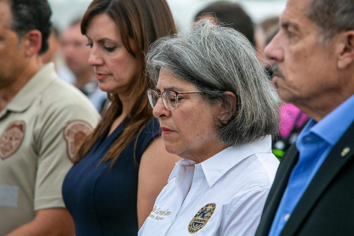 Miami-Dade County Mayor Daniella Levine Cava, center, prays with other officials in front of the rubble that once was Champlain Towers South. The large group of officials, search and rescue team members, police and other workers gathered at the site of the condo collapse for a moment of prayer and silence early in the evening on Wednesday, July 7, 2021, in Surfside, Florida.