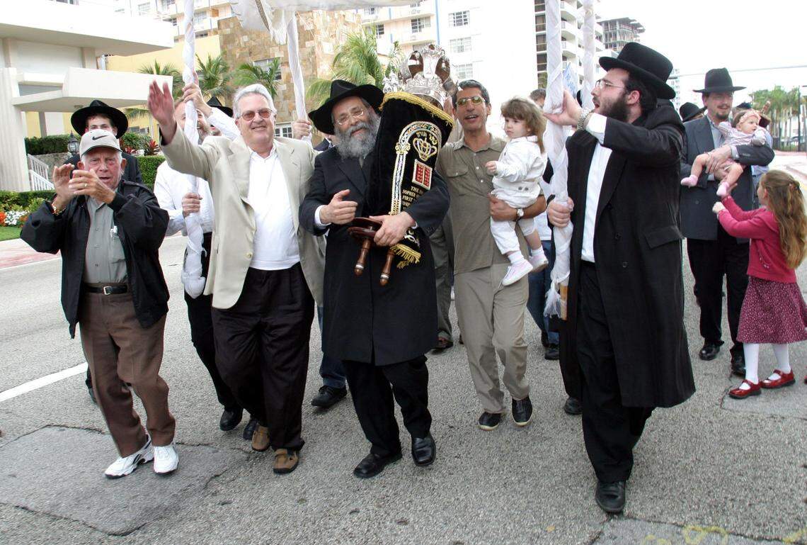 Dade--2-15-04--Joshua Prezant/ for the Herald--Hank Jacob Sopher ( second from left) and Sholom D. Lipskar ( middle with Torah), the Rabbi of The Shul, dance out on Collins Avenue during lat part of the ceremony and party for the completion of the first Sefer Torah ever written in Florida. The Final letters were placed in the Torah at The Shul, 9540 Collins Avenue, during the ceremony.