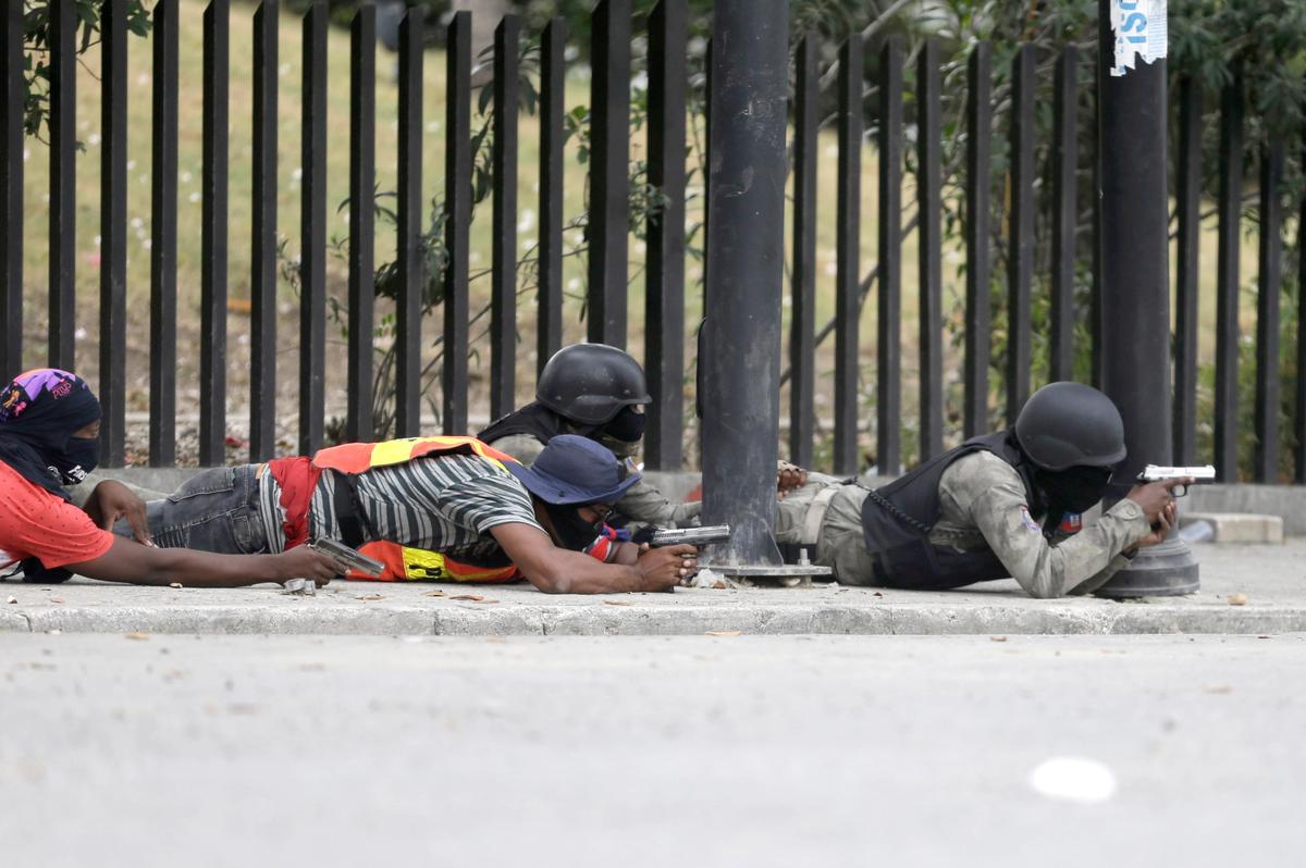 Armed off-duty police officers take cover during an exchange of gunfire with army soldiers during a protest over police pay and working conditions, in Port-au-Prince, Haiti, Sunday, Feb. 23, 2020.
