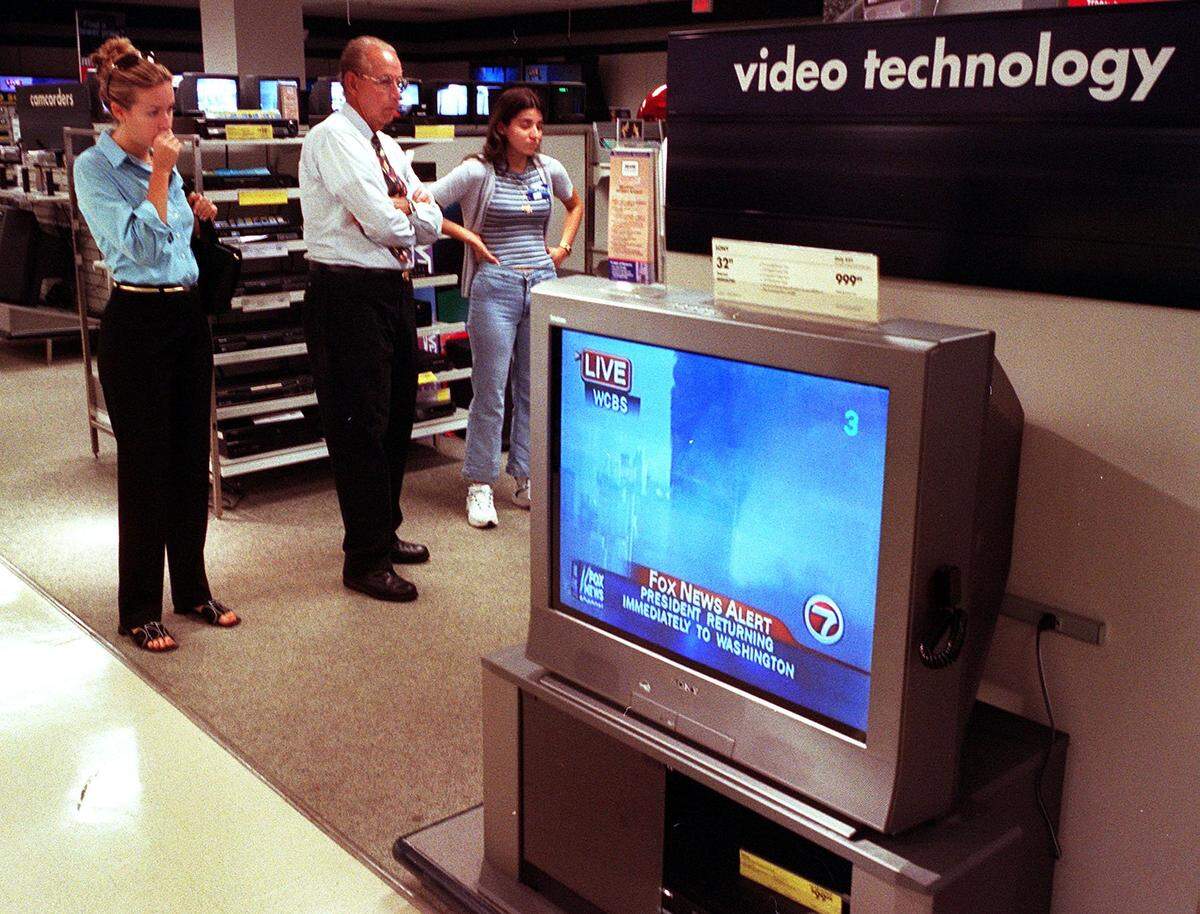 In this file photo from Sept. 11, 2001, Sears employees and customers at the Douglas Road and Coral Way Sears watch in horror from the TV and electronics department while watching local TV live reports of the terrorist attack on the World Trade Center in New York City that morning.