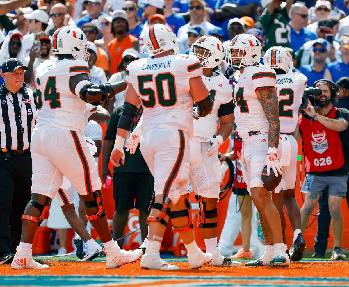 Miami Hurricanes tight end Cam McCormick (84) celebrates with teammates lineman Francis Mauigoa (61) and Isaiah Horton (2) after scoring a touchdown during the first half of an NCAA college football game against the Florida Gators at Ben Hill Griffin Stadium in Gainesville, Florida, on Saturday, August 31, 2024.