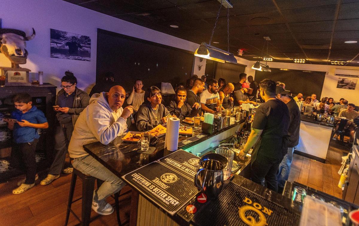 After waiting patiently outside for their turn, customers eat at the bar of Apocalypse BBQ in Kendall.