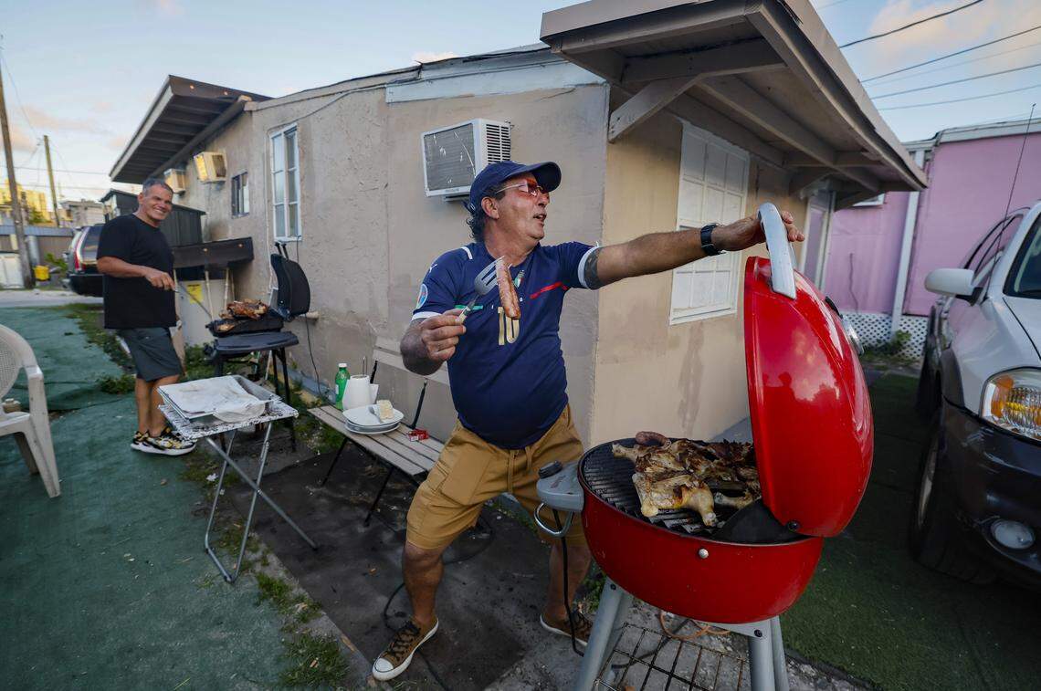 Jorge Junir Alvarez dances to music coming from a boom box as Rodolfo Sanchez reacts while they both grill meat for fellow tenants at Silver Court Mobile Home Park in Little Havana in Miami, Florida, on Friday, April 17, 2026. The trailer park is closing as 200 families will soon be evicted to make room for development.