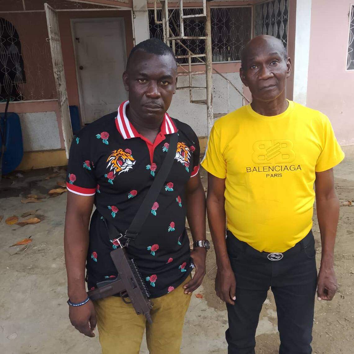 Prosecutor Jeir Pierre with the gun strapped to his chest was in Bassin-Bleu on Saturday, September 20, 2025 after a criminal gang attacked the rural community in northwest Haiti. He is standing next to Mayor Tony Manigat, whose office inside town hall was also set ablaze by the gunmen.
