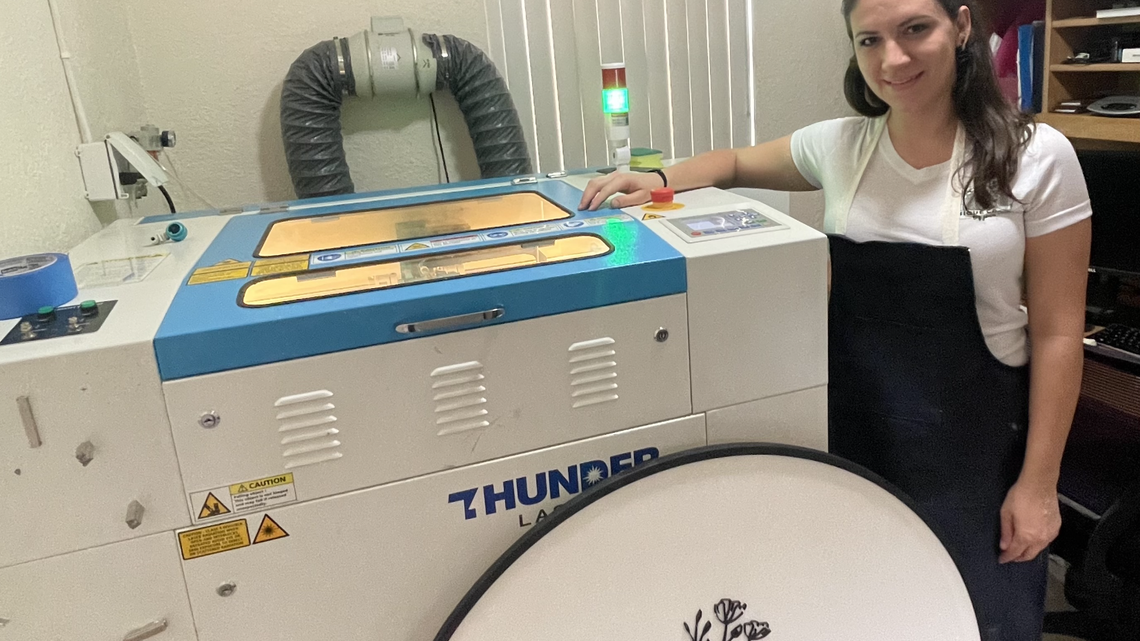 Kendall mother Jennifer Arniella, 29, stands in front of the laser-cutting machine she bought for her home-based business.