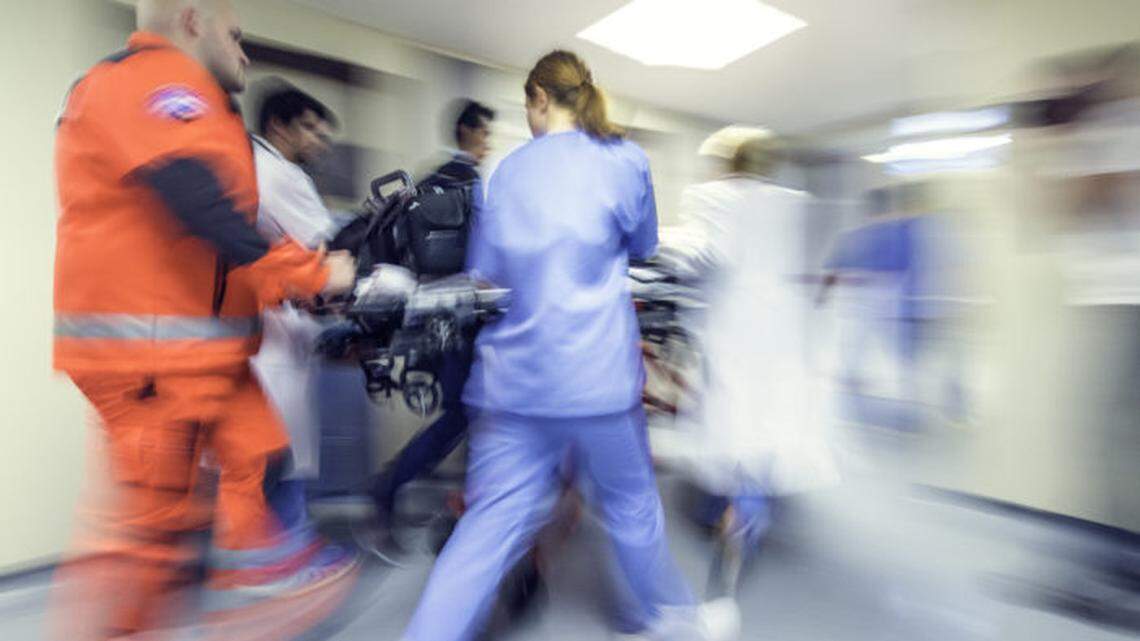 Paramedics and a nurse rush a gurney through a hospital corridor.