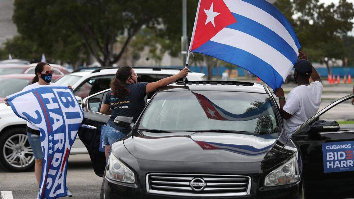 From left, Cynthia Perez, Amore Rodriguez and Raymond Adderly decorate their vehicle with a Biden and a Cuban flag as they wait for the arrival of former President Barack Obama to speak in support of Democratic presidential nominee Joe Biden during a drive-in rally on Oct. 24, 2020, in North Miami, Florida. Obama was campaigning for his former vice president before the Nov. 3 election.