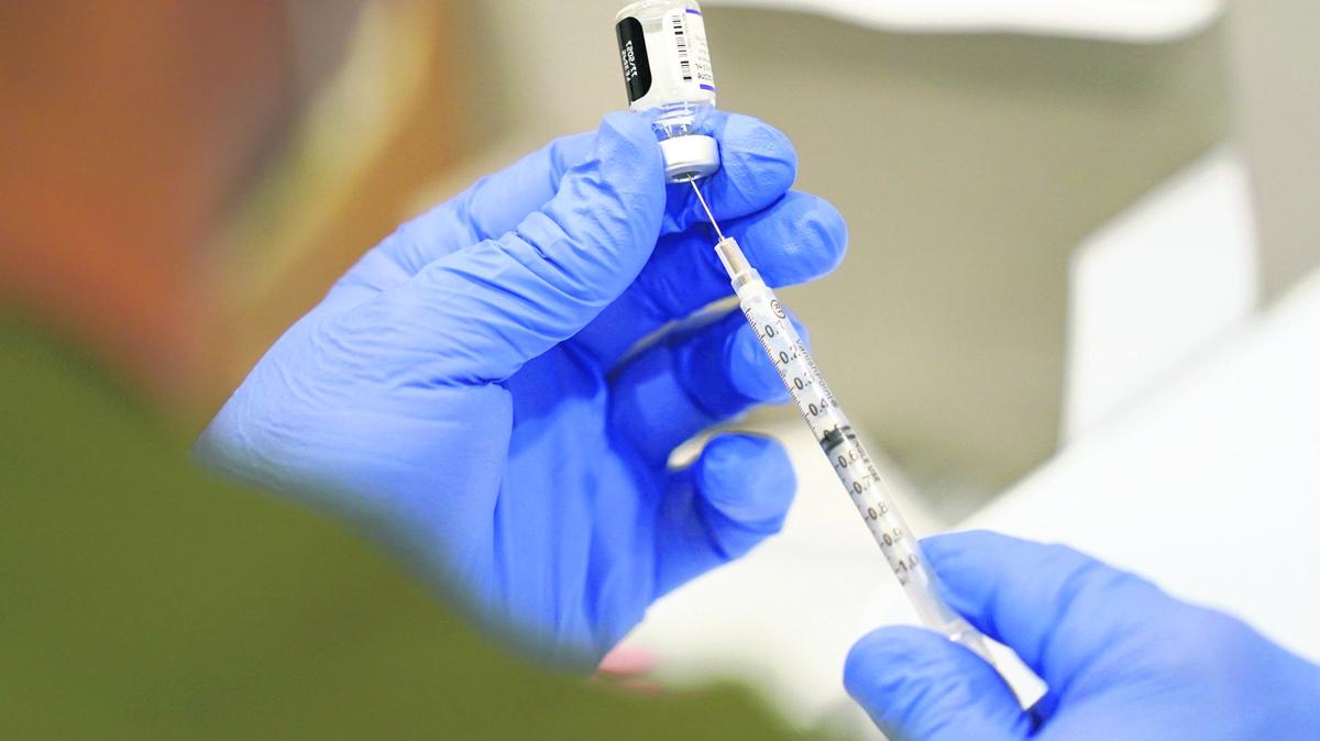 A healthcare worker fills a syringe with the Pfizer COVID-19 vaccine at Jackson Memorial Hospital in Miami. At least 44 hospitals are expecting to have a critical staffing shortage within a week, according to data collected Jan. 11 by the U.S. Department of Health and Human Services.