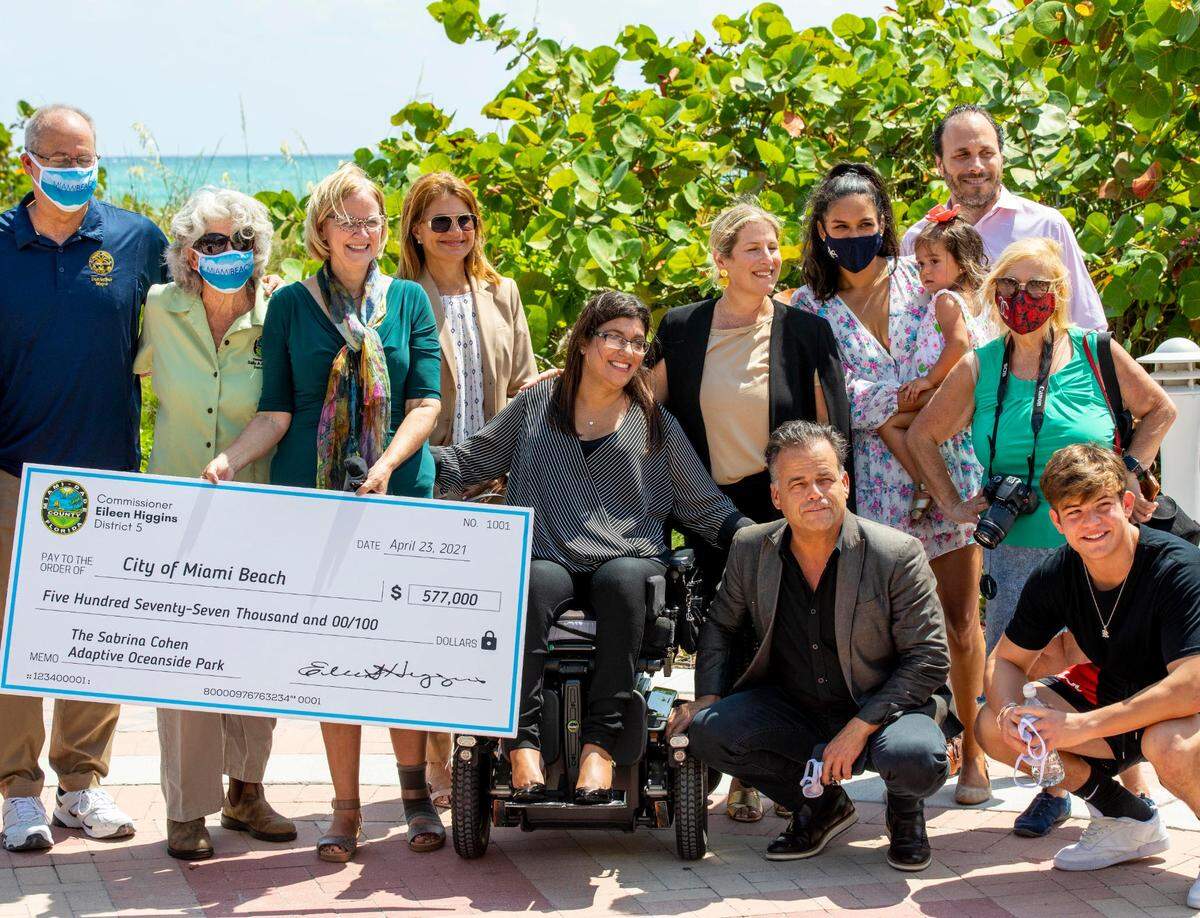 Disability-rights activist Sabrina Cohen is presented with a check for $577,000 during a press conference to announce the planned construction of a new park and beachfront wheelchair-accessible viewing platform at the site of the current Beach View Park & Vita Course in Miami Beach, Florida, on Friday, April 23, 2021. The $680,000 project, funded mainly by Miami-Dade County, will redevelop the city’s existing Beach View Park at 5301 Collins Ave. with adaptive playground and exercise equipment.