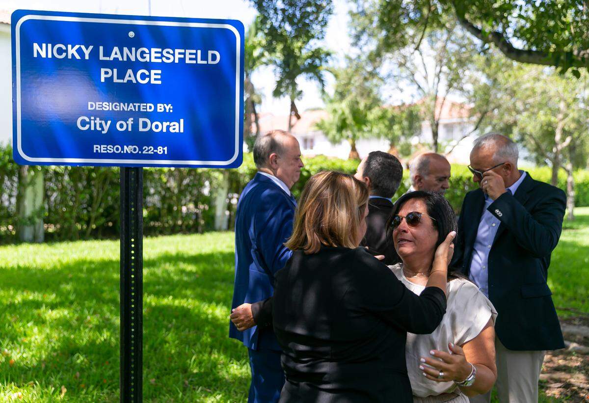 Andrea Langesfeld is hugged as she participates in a ceremony for her late daughter, Nicole “Nicky” Langesfeld, on Wednesday, June 22, 2022 in Doral, Fla. Ahead of the one-year anniversary of the Surfside condo collapse Friday, victim Nicole Langesfeld, 26, was honored by the City of Doral as they unveiled the newly co-designated NW 114th Avenue between NW 41st Street and NW 50th Street as Nicky Langesfeld Place.