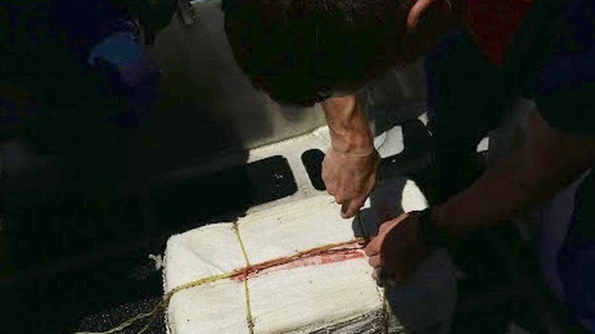 A U.S. Coast Guard crew member cuts into one of six bales of cocaine that were found off the Florida Keys between Saturday, Aug. 3, and Monday, Aug. 5.