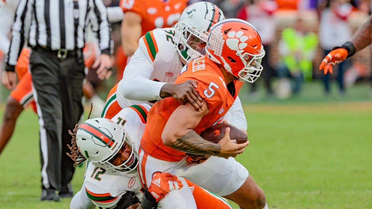Miami Hurricanes defensive lineman Nyjalik Kelly (32) and defensive lineman Jahfari Harvey (12) Clemson Tigers quarterback DJ Uiagalelei (5) in the first quarter at Frank Howard Field at Clemson Memorial Stadium in Clemson, South Carolina on Saturday, November 19, 2022.