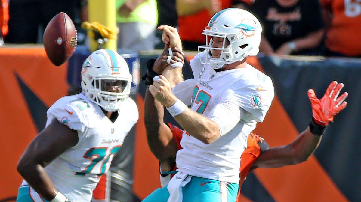 Dolphins quarterback Ryan Tannehill fumbles the ball Sunday as Cincinnati Bengals defensive lineman Carlos Dunlap grabs his arm in the fourth quarter of the Bengals’ comeback win.