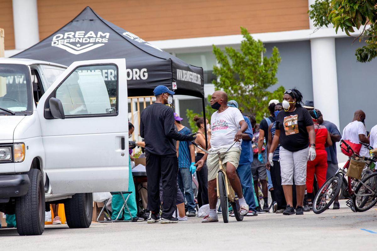 Dr. Armen Henderson, the young doctor who was handcuffed in front of his Flagami home two weeks ago while loading tents to give out to those living in the streets of Downtown, speaks with a member of the homeless community during an event hosted by The Dream Defenders, in order to aid the unhoused at St. John Institutional Missionary Baptist Church in Overtown, Florida on Friday, April 24, 2020.