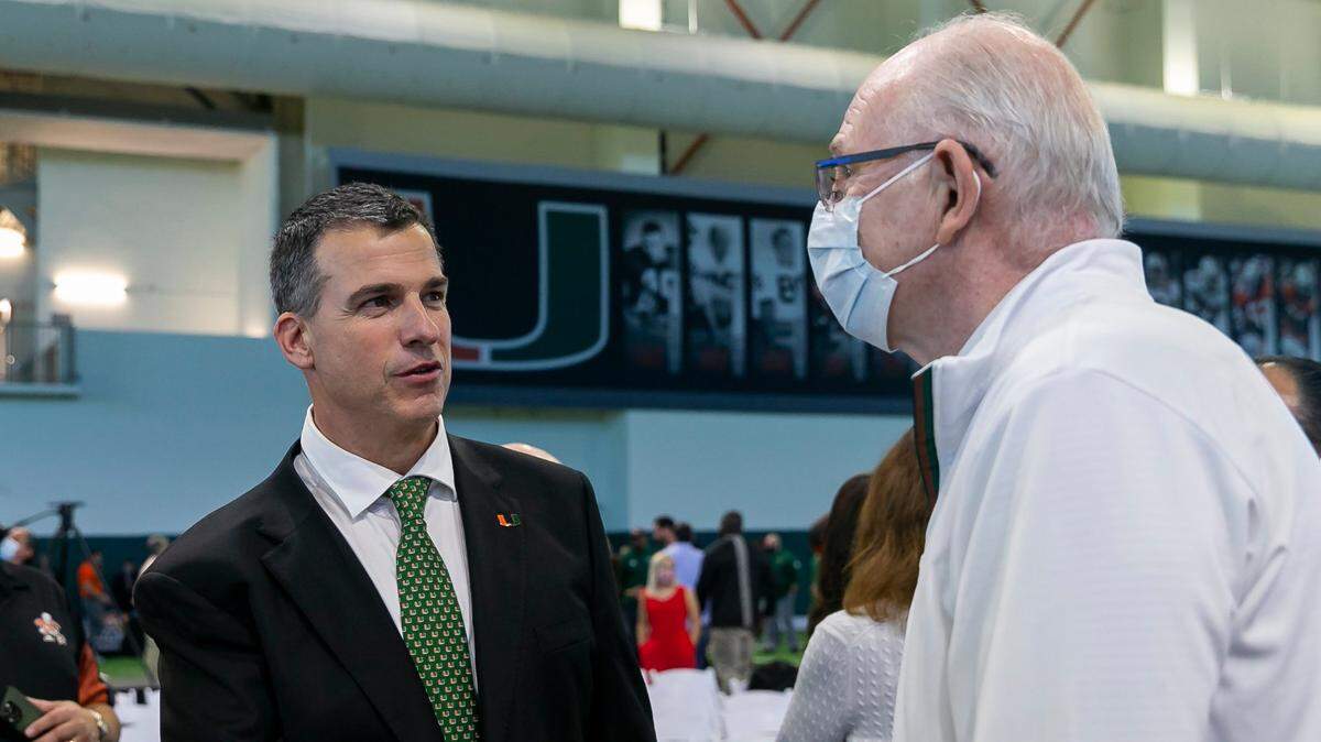Mario Cristobal, the newly hired head football coach of the Miami Hurricanes, shakes hands with Miami Hurricanes basketball head coach Jim Larrañaga after a press conference at the Carol Soffer Indoor Practice Facility inside the University of Miami in Coral Gables, Florida on Tuesday, December 7, 2021.