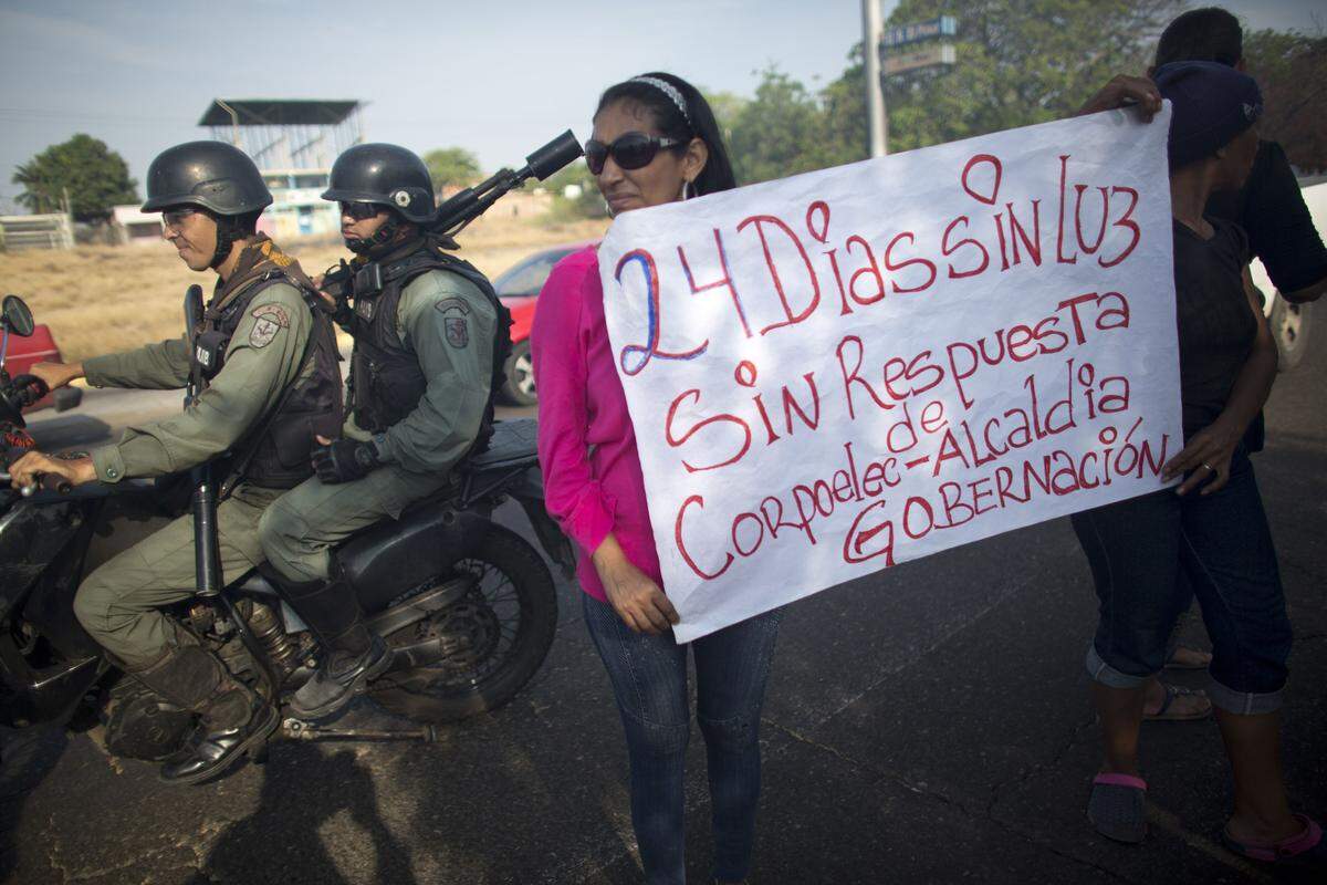 In this April 18, 2018 photo, residents of La Chinita neighborhood hold a sign with a message that reads in Spanish: "24 days without light, without answers", during a protest in Maracaibo, Venezuela. Blackouts are nothing new under two decades of socialist rule in Venezuela. But they've grown more frequent, and are lasting longer. (AP Photo/Ariana Cubillos)