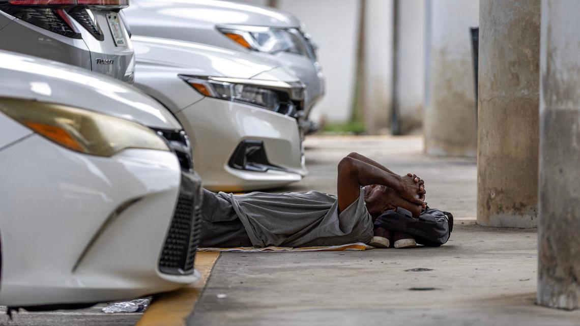 A man sleeps inside a parking lot underneath the expressway while waiting for the nonprofit One World One Heart to deliver free meals to the homeless population on Thursday, Sept. 12, 2024, in Miami.