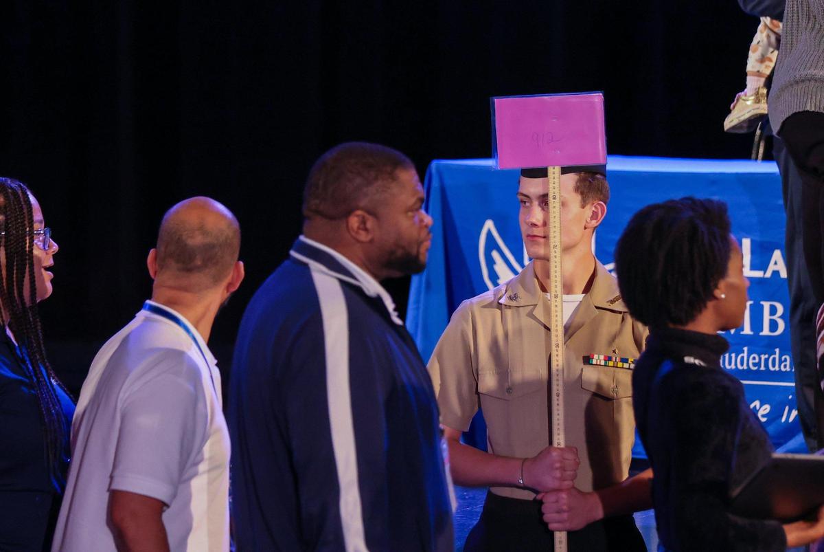 NJROTC cadet, Caydan Caramanna, right, holds a sign to direct the “pink” break-out group to their location at Broward County Public Schools’ first of three town halls about school closures.