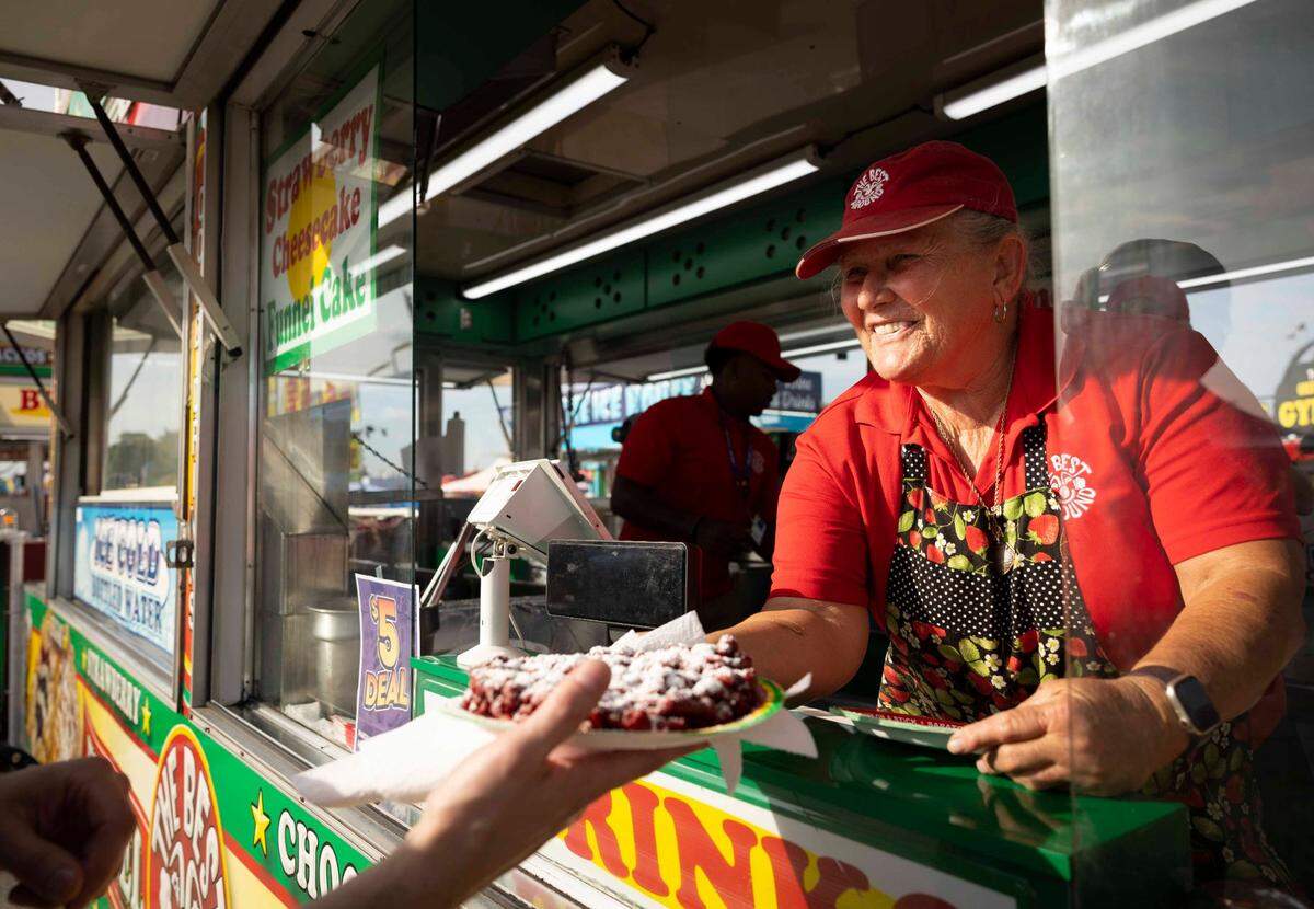 Mama Jane serves a customer a red velvet funnel cake during the Youth Fair opening day on Thursday, March 14, 2024, at the Miami-Dade Fair and Exposition.