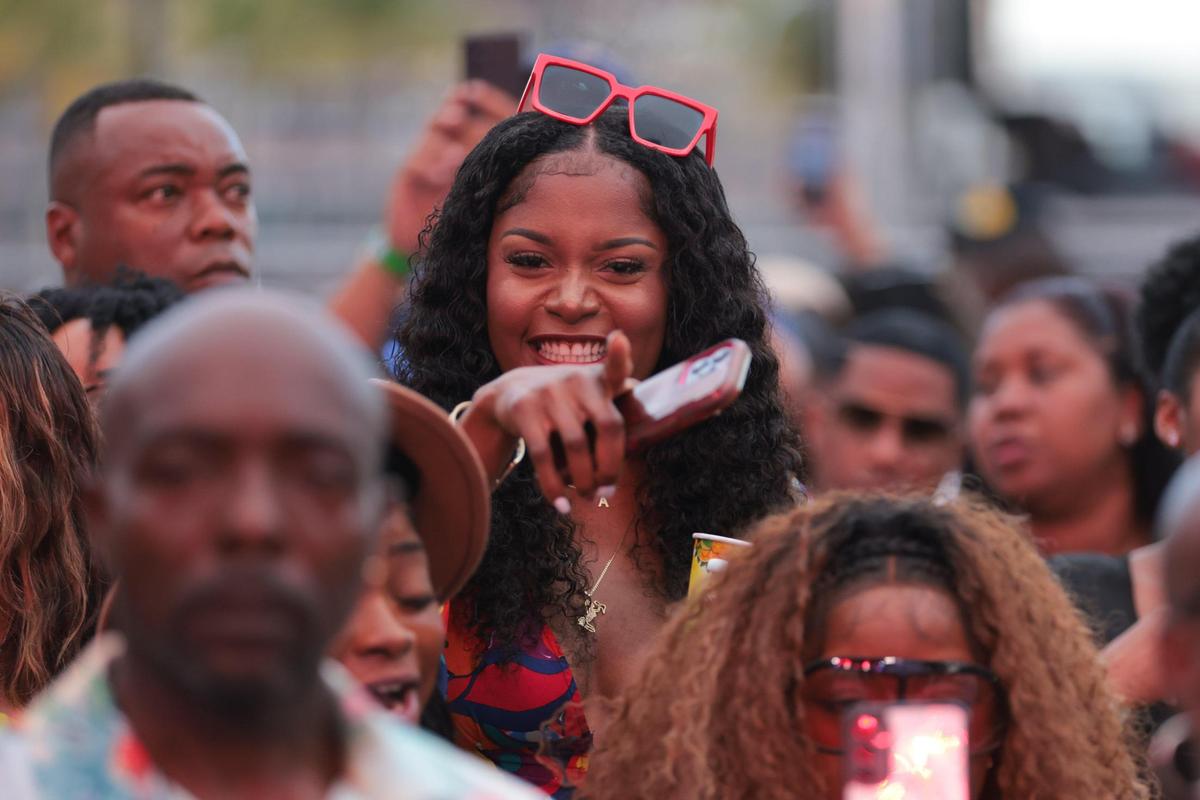 A woman in the audience signals while enjoying a concert during the 19th annual Best of the Best International Music Festival at Bayfront Park in downtown Miami, Sunday, May 25, 2025. Despite the large crowd, concertgoers could view and hear the performance thanks to a screen set up in the middle of the park.
