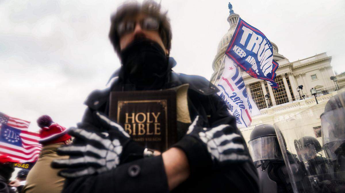 In this Wednesday, Jan. 6, 2021 file photo, a man holds a Bible as Trump supporters gather outside the Capitol in Washington. The Christian imagery and rhetoric on view during this month’s Capitol insurrection are sparking renewed debate about the societal effects of melding Christian faith with an exclusionary breed of nationalism.