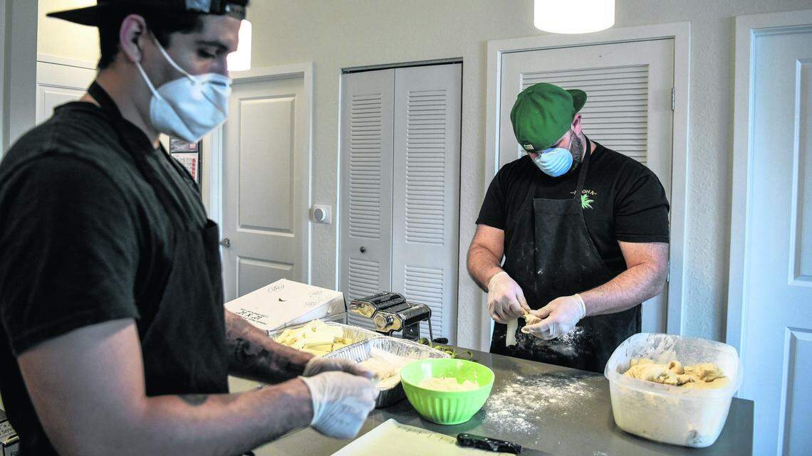 Rafael Delgado, left, and his business partner Mario Amate, who both worked as Uber drivers until they recently found themselves unemployed, prepare tequenos, a popular Venezuelan snack, inside Amate’s home in Miami, on April 21, 2020.