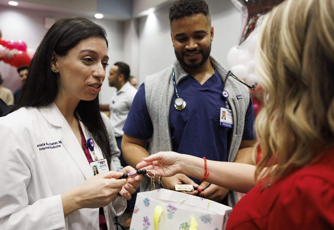 Priscilla Timmons, former ICU coma patient, hands out “Miracle Worker” keychains to her intake doctor, Daniela Bou Daher, left, and her discharge doctor, Johnathan McQuire, center, after a gathering reuniting Timmons with therapy dog Scrunchie and the rest of her care team on Wednesday, Oct. 22, 2025, at Memorial Hospital West in Pembroke Pines, Fla.