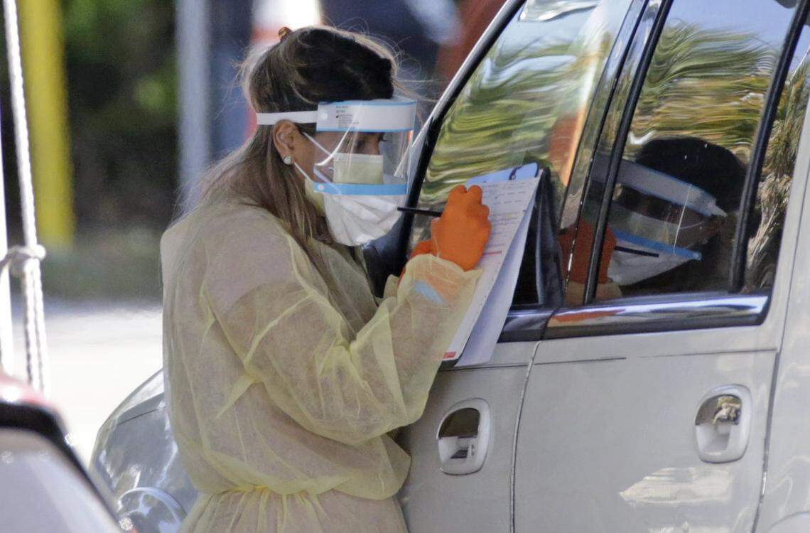 A Healthcare worker help to check in with the assistant from the Florida Army National Guard as vehicles line up at the COVID-19 drive-thru testing center at Marlins Park as the coronavirus pandemic continues on Wednesday, March 25, 2020 in Miami.