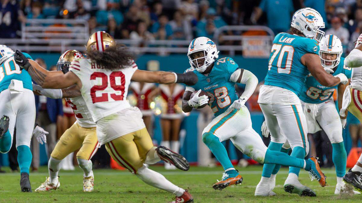 El running back de los Dolphins, De’Von Achane (28), corre con el balón mientras el safety de los 49ers de San Francisco, Talanoa Hufanga (29), trata de detenerlo en el partido celebrado el 22 de diciembre de 2024 en el Hard Rock Stadium en Miami Gardens, Florida.