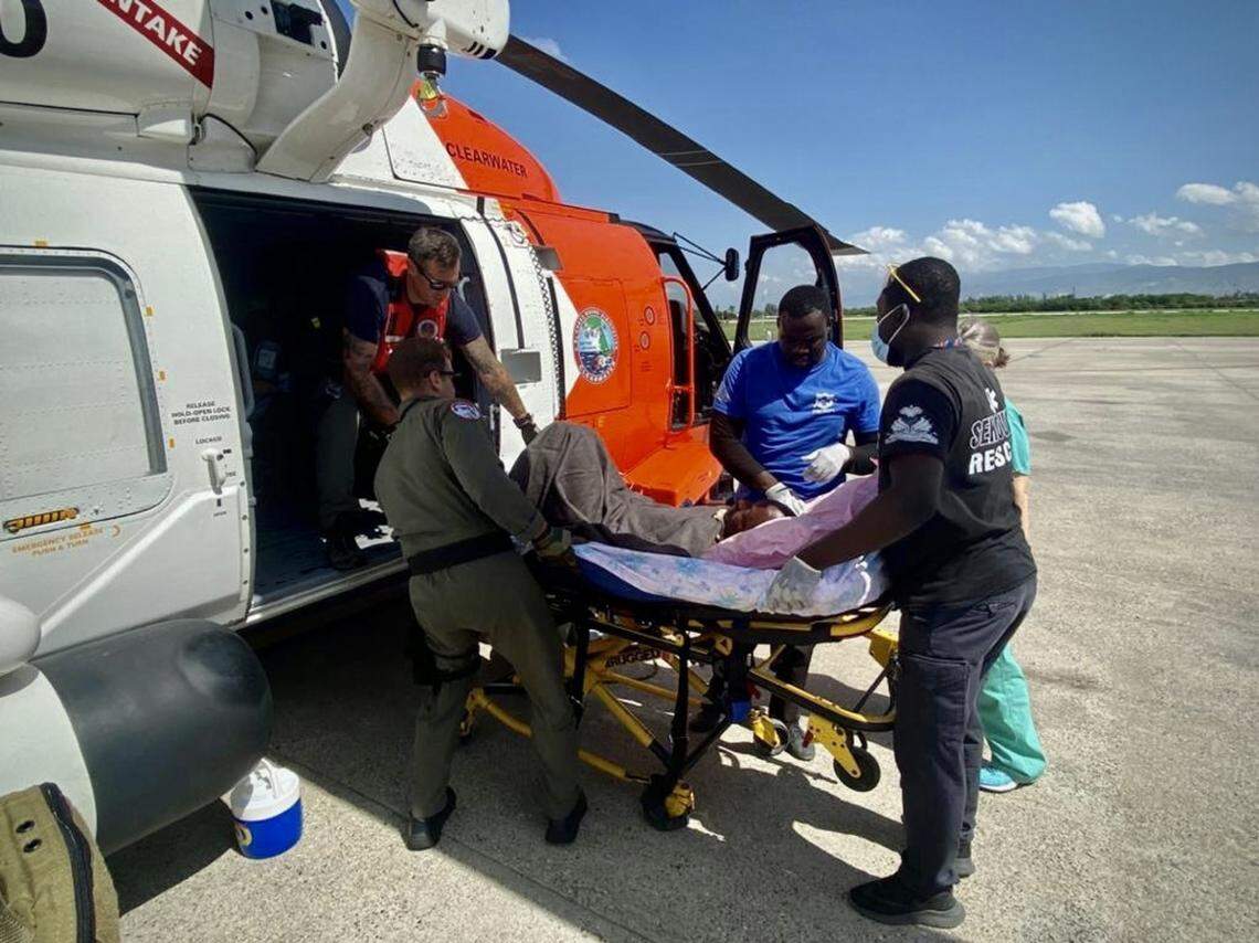 U.S. Coast Guard members and Haiti emergency medical services members remove a critically injured Haitian citizen from the helicopter in Port-au-Prince, Haiti, on Aug. 15, 2021. The Coast Guard deployed Jayhawk helicopter crews from its Air Station in Clearwater, Florida.