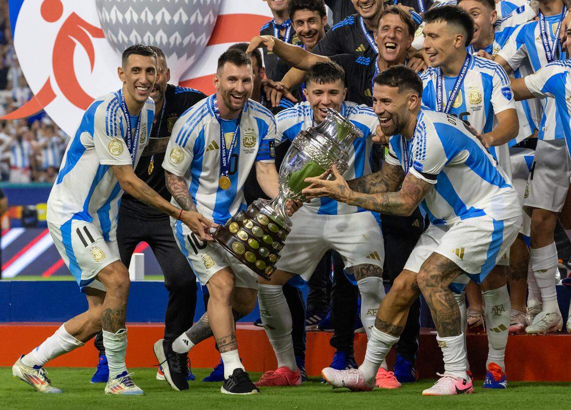 Argentina players Ángel Di Maria (11) Lionel Messi (10) Enzo Fernández (24) and Nicolás Otamendi (19) hold the trophy with his teammates after defeating Colombia in their Copa America 2024 Final soccer match at Hard Rock Stadium on Sunday, July 14, 2024, in Miami Gardens, Fla.